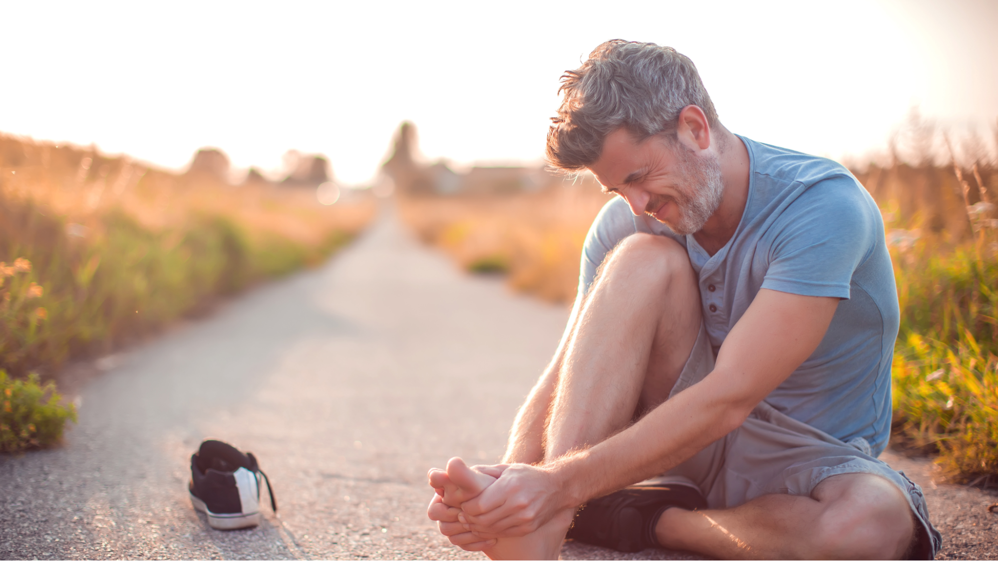 man on outdoor trail in pain with arthritis in his feet