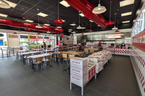 Image of the dining room of the Five Guys restaurant at 17819 Tamiami Trail  in North Port, Florida. Photo shows tables, chairs and Five Guys signage.