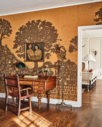 Study desk with muraled wall, wooden table, and doorway leading to a bedroom.