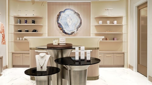 Luxurious spa with modern decor, a central display of skincare products and jewelry, soft lighting and a large agate wall accent