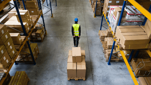man using a hand lift to move boxes in a warehouse