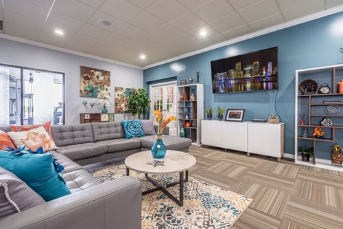 Modern living room with gray sectional sofa, blue accent wall, and city skyline television display.