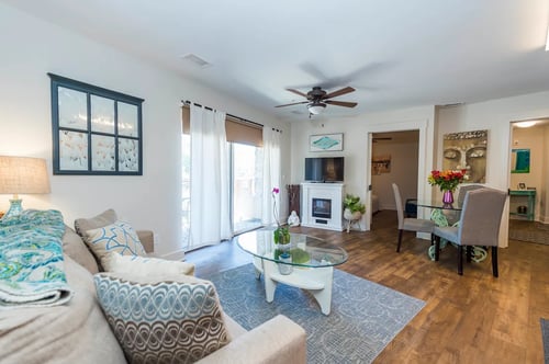 Spacious Living area with ample light, hardwood floors, a white couch and table and a fireplace near a patio at Roaring Fork Apartments in Basalt, CO 81621