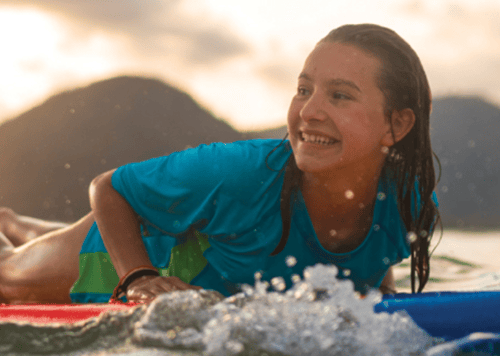 young teen girl on surfboard in water