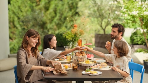Eine Familie genießt ein entspanntes Frühstück im Freien. Frisch gebackenes Brot, Croissants und Brötchen stehen auf dem Tisch. Morgengold bringt regionale Backwaren frühmorgens an die Haustür – bequem, zuverlässig und mit höchster Qualität.