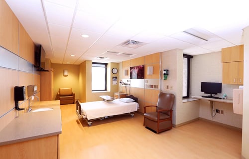 Another view of the birthing room showing bed, chairs, TV, and sink.