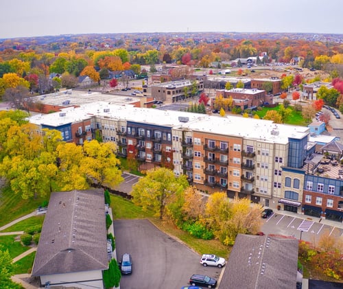 Aerial view of an apartment complex surrounded by fall trees at Victoria Flats Logo in Victoria, MN 55386
