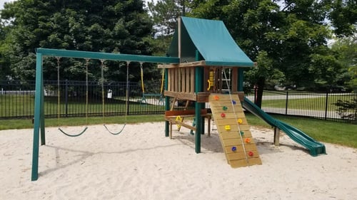 A playground with a green slide and a wooden structure at Highlands of Heritage Woods, Ohio