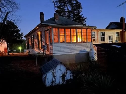 White house with lights on inside at dusk