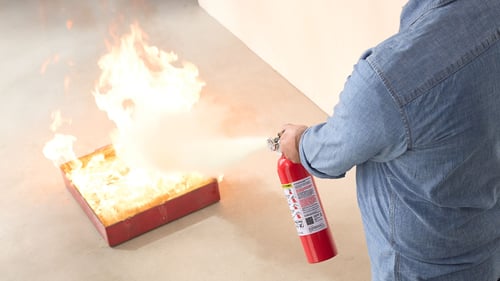 Man using a Kidde fire extinguisher.