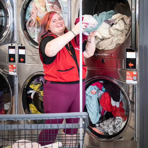 Speed Queen Laundry attendant unloading clothes from a commercial dryer