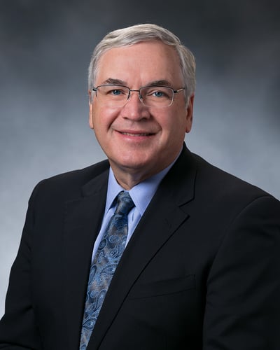 Dr. Will Hurley smiling in front of a gray background.