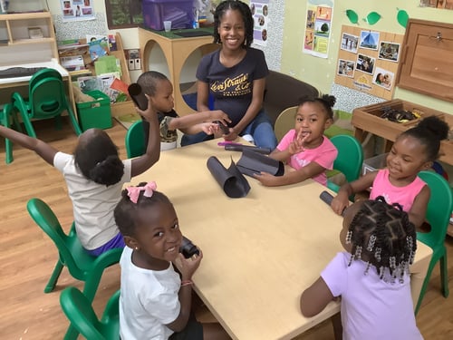 Children working together on a large group art project, using paints and markers.