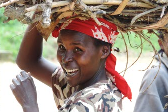 Femme souriante portant un foulard rouge et transportant un bébé sur son dos dans un tissu traditionnel coloré au centre communautaire rwandais