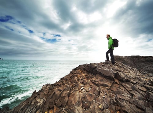 Man standing rock looking at ocean