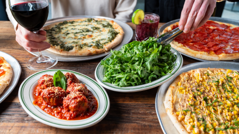Table with pizzas, appetizers and wine