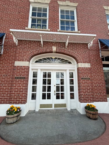 White double doors in an arched red brick building entrance.