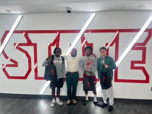 Team Member Trevor with one of the Players of the week in front of white wall with red writing