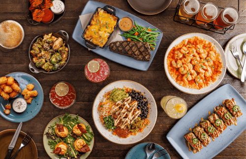 Large shareable feast with grilled steak, firecracker shrimp, brussels sprouts, a chicken bowl, tater tots, deviled eggs, and a beer flight.