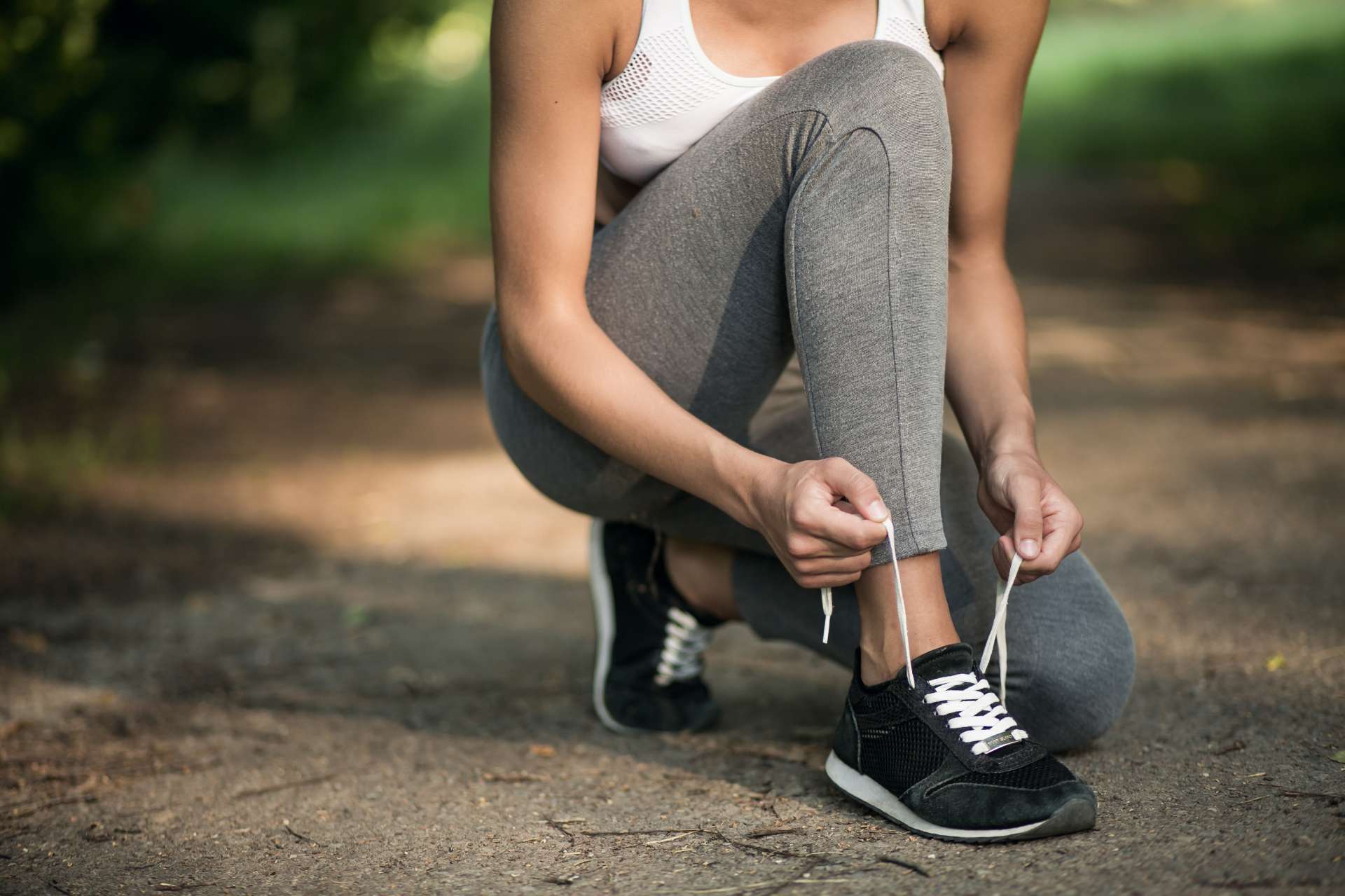 woman on trail outside tying shoe for better arch support