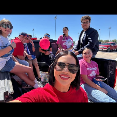 Agent Sophia sitting and smiling with team members and children in the back of the gray State Farm truck