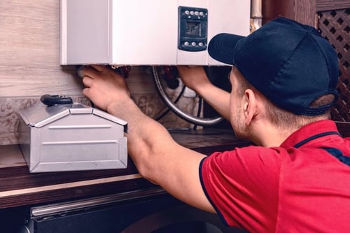 Technician inspecting a water heater and pipes to prevent leaks.