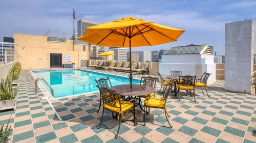 A yellow umbrella is on a table with chairs around it at The Langham, Los Angeles, CA, 90005