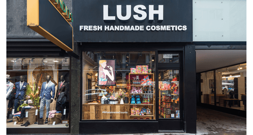 Shopfront, large glass window with black frame. Logo above in white on black background.
