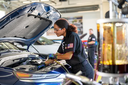 Valvoline technician performing oil change service on customer vehicle, complete within 15 minutes.