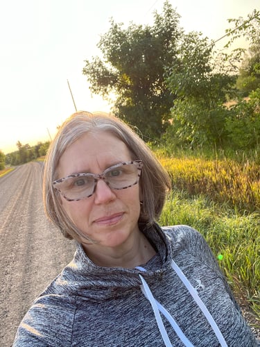 Colleen, on a dirt road, surrounded by scenery and trees