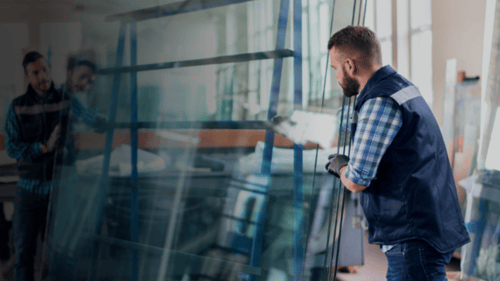two men carrying sheets of glass