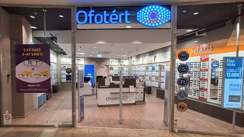 Ofotért üzlet bejárata Budapesten, az Árkád bevásárlóközpontban, üvegportálos homlokzattal és kivilágított belső térrel.