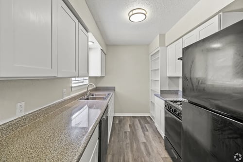 A modern kitchen with a black oven and a granite counter top at La Bella Apartments, Fort Worth, TX