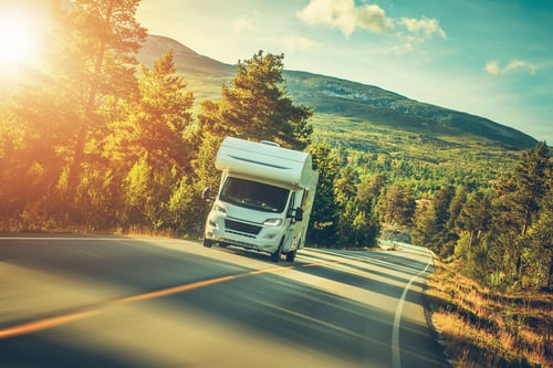 A camper van set against a beautiful natural backdrop, ready for a summer road trip adventure.