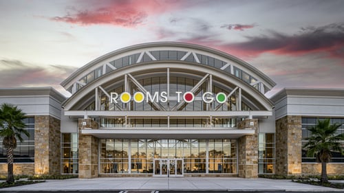 Rooms To Go showroom exterior with modern architecture and sunset backdrop