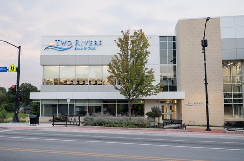 Front of a building, a large tree with Two Rivers