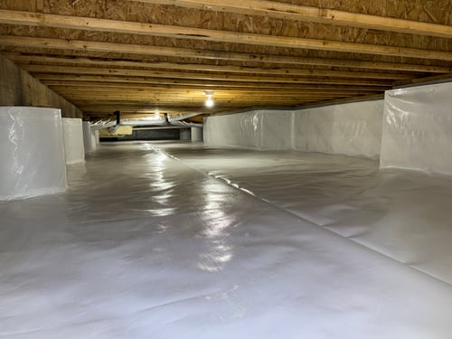 White vapor barrier lining the floor and walls of an encapsulated crawl space