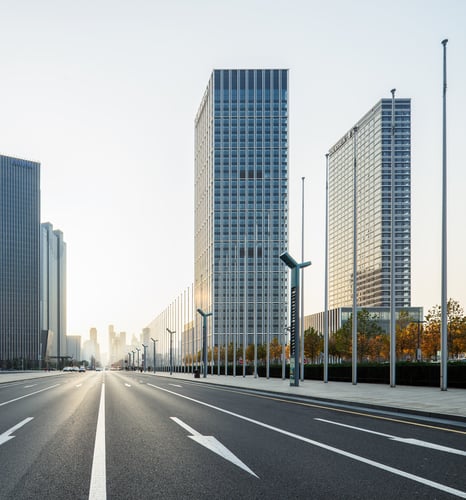 linear perspective of high rise buildings while looking down a one-way street with no traffic