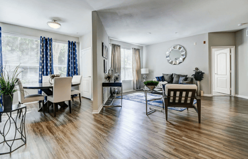 Large, open-concept living area with plank flooring, large windows, and a separate dining area at Tuscany Bay Apartments in Tampa, FL