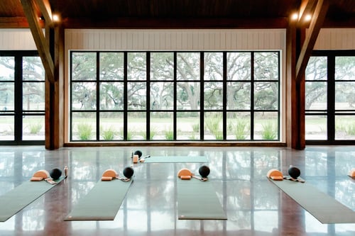 Yoga mats and exercise balls arranged in a spacious studio with large windows.