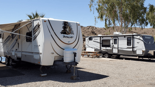 two RVs parked next to the water