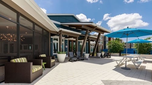 pool deck at lake nona ariel with clubhouse to the left and blue umbrellas to the right
