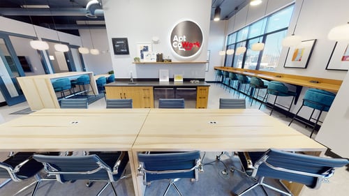An eight-person community table and small kitchen with a mini-fridge
