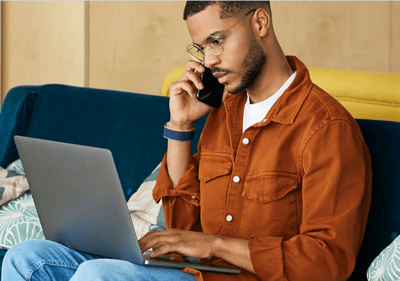 man looking at computer while talking on telephone