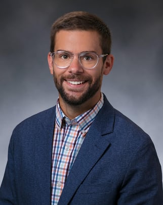 Dr. Edwall Joel smiling in front of a gray background.