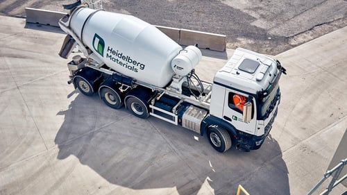 Overhead view of a Heidelberg Materials cement mixer truck with a driver in high-visibility clothing.
