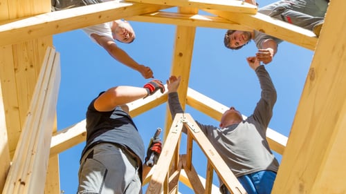 Group of builders workjing on frame of roof