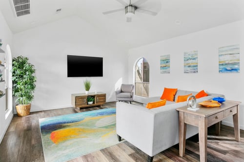 A living room with a grey couch and orange pillows at Central on Broadway in Mesa, AZ