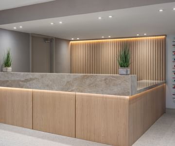 Modern marble and wood hotel reception desk with plants at The Harrison Hotel Downtown Hollywood