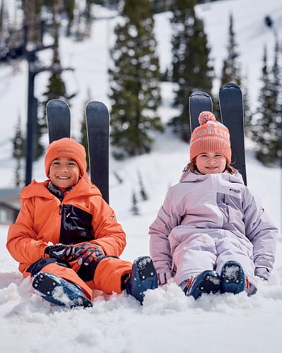 Two kids sitting in snow.